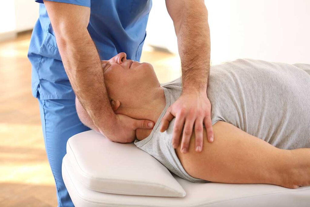 A person seated on a living room floor gently stretching their neck with one hand, appearing relaxed and focused.