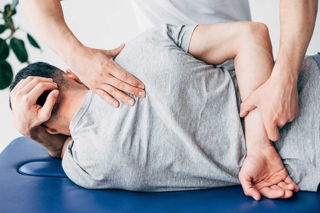 Pregnant woman lying on her side with cushions while receiving a gentle back adjustment